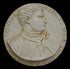 photo of off-white plaster cast relief sculpture of small medallion of male portrait in profile, namely Giovanni de Medici, and text around the edge on black background