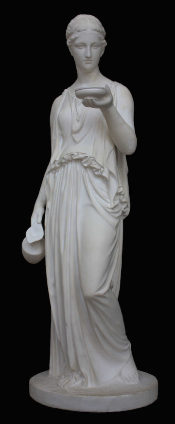 photo with black background of plaster cast sculpture of goddess Hebe in robes standing and holding a jug in right hand at her side and a bowl in left hand raised in front of her